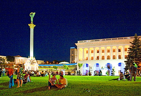 Ukraine Kiev Place of Independence with column of independence building of national akademie of music Cajikovskij Conservatorium music arrangement national holiday people on the place celebrating drinking laying in parkmeadows night after sunset people ar