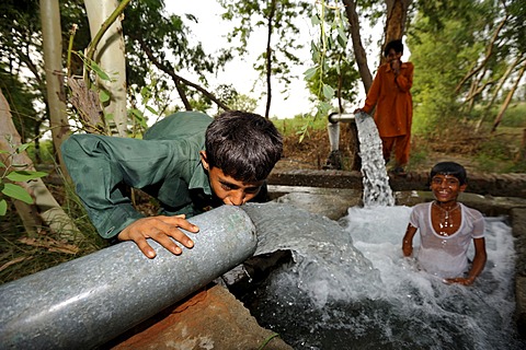 Children cooling off at the catchment of a spring that is fed by water pipes, Basti Lehar Walla village, Punjab, Pakistan, Asia