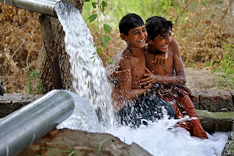 Children cooling off in the catchment of a spring fed by water pipes, Basti Lehar Walla village, Punjab, Pakistan, Asia