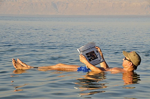 Tourist reading the newspaper in the Dead Sea, high salt content, near Suwaymah, Jordan, Middle East, Orient