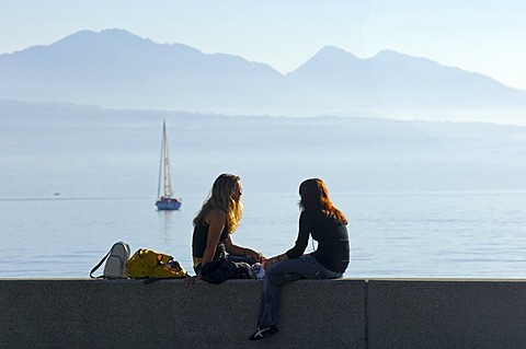 Young women chatting on a wall at Lake Geneva, Lac Leman, Ouchy, Lausanne, Switzerland