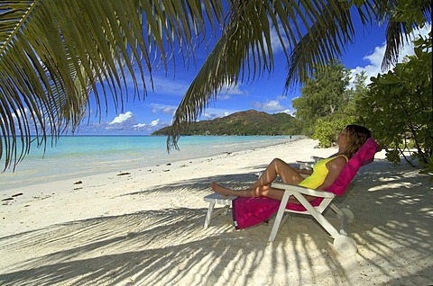 Young woman on deck chair, sleeping under palm trees, Praslin Island, Seychelles, Africa