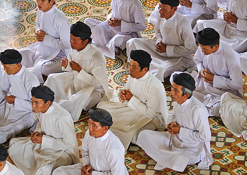 Praying devout men, ceremonial midday prayer in the Cao Dai temple, Tay Ninh, Vietnam, Asia