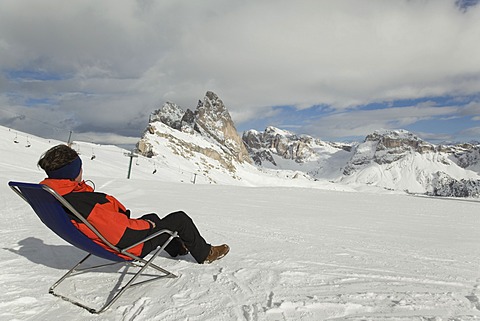 Man sitting in a deck chair on ski slope, Sella Massif, Dolomites, South Tyrol, Italy