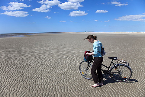 Woman walking barefoot with a bike on the widest beach in northern Europe, Havsand, island of RÃ¸mÃ¸, TÃ¸nder, Denmark, Europe