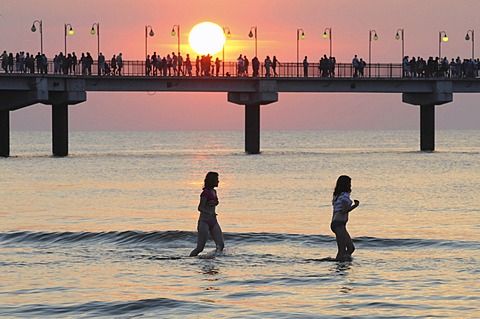 The pier in sunset and bathing girls, Miedzyzdroje, Poland, Europe