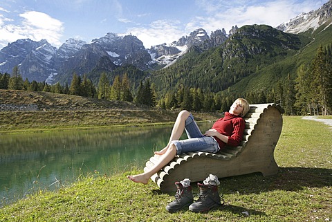 AUT, Austria, Fulpmes, Stubai Valley: Hiking path in the mountains to the Schlickeralm. Relaxing at the Speichersee lake on wooden chairs and beds. |