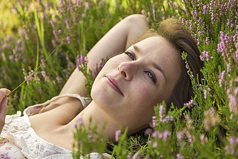 Young woman lying on a heather carpet