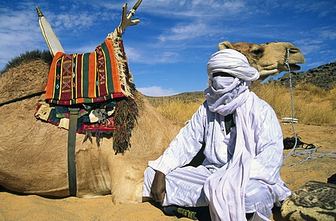 Tuareg man sitting beside his camel, Libya, North Africa