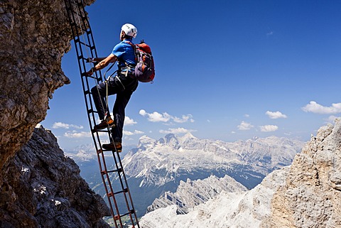 Mountain climber ascending the Via Ferrata Marino Bianchi climbing route on Cristallo di Mezzo Mountain, overlooking the Tofane Mountains, Dolomites, Belluno, Italy