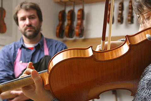 Violin-maker (luthier) with a customer in his shop