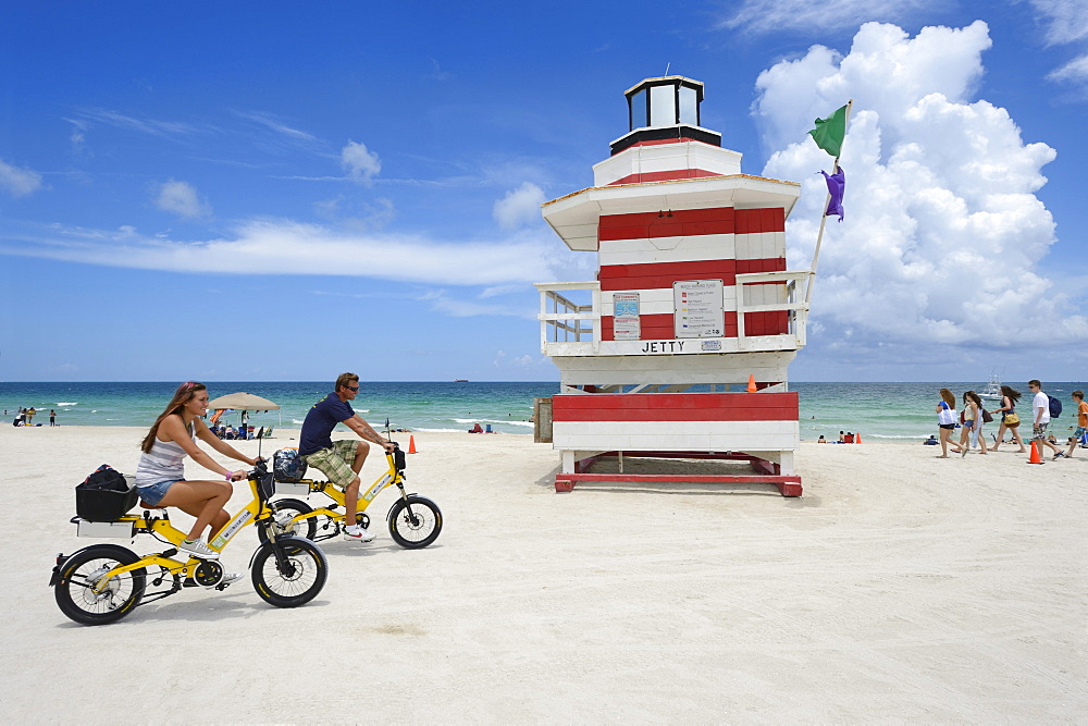 Couple riding electric bicycles, Watchtower, The Jetty, Miami Rescue Tower, South Beach, Miami, USA