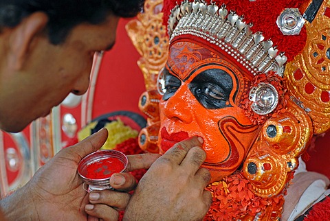 Painting the face of a Theyyam performer, preparing for a ritual, near Kasargod, North Kerala, South India, Asia