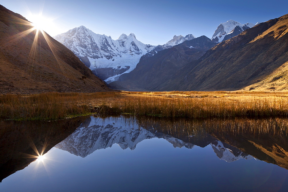 The morning sun and mountain peaks being reflected in lake Laguna Jahuacocha, Cordillera Huayhuash mountain range, Peru, South America