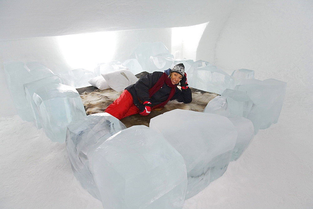 Tourist lying on a bed in a hotel room of the ice hotel in Jukkasjaervi, Lappland, Northern Sweden