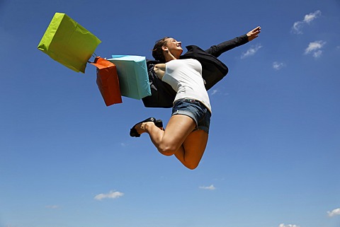 Woman jumping with shopping bags, joyful leap