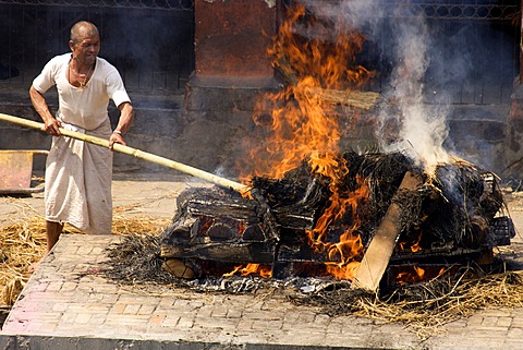 Traditional funeral, untouchable priest of the lowest caste tending pyre, Pashupatinath, Nepal, Asia