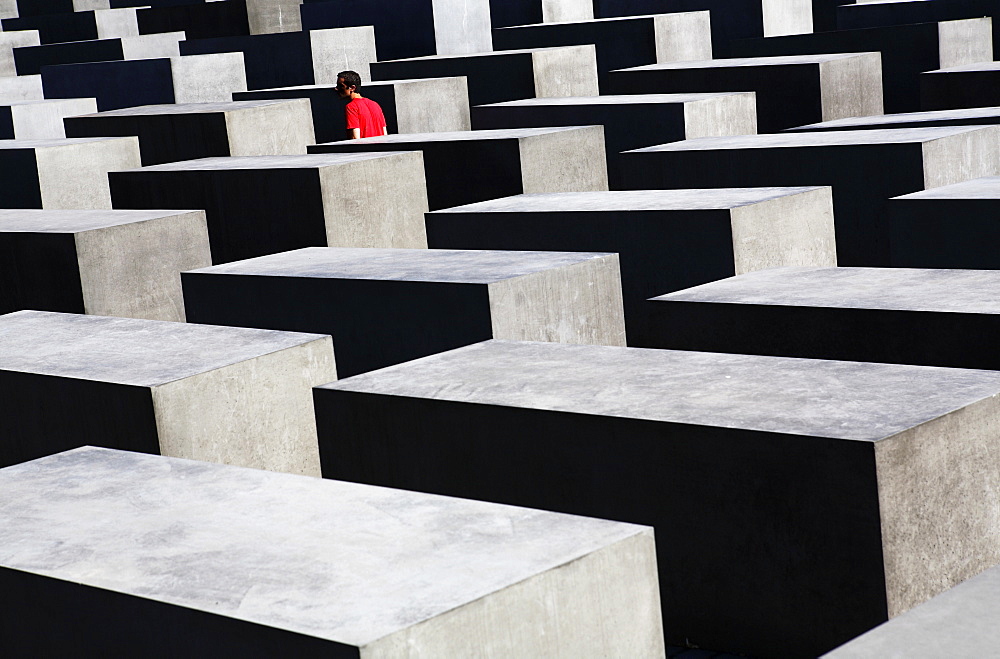 Lone person among concrete slabs at the Holocaust Memorial (Memorial to the Murdered Jews of Europe), Berlin, Germany