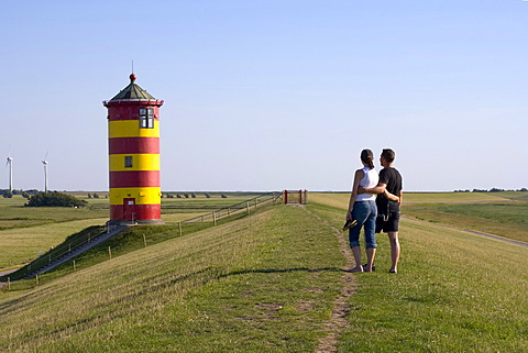 Couple strolling in front of Pilsum Lighthouse, Pilsum, Krummhoern, East Frisia, Lower Saxony, Germany, Europe