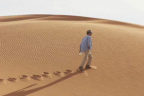 Man is walking along a sanddune, Lybia