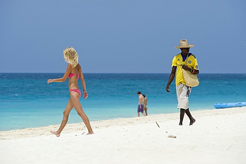 Souvenir seller and female holidaymaker on the beach of Kendwa Rocks, north coast of Zanzibar, Tanzania, Africa