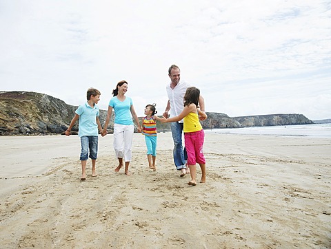 Woman, man, two girls and a boy walking along the beach, hand in hand, laughing, Bretagne, France, Europe