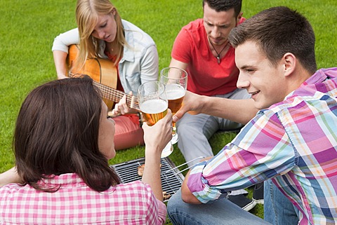 Group of young people at a barbecue with beer and a guitar in the garden