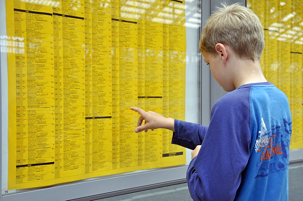 School boy, 9, studying the train timetable, Central railway station in Cologne, North Rhine-Westphalia, Germany, Europe