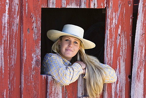 Cowgirl looking out of barn-window, wildwest, Oregon, USA