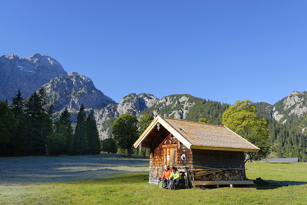 Hikers resting wooden hut, snacking, Rohntal at Purschalm, Eng, Karwendel, Risstal, Rissbachtal, Tyrol, Austria, Europe