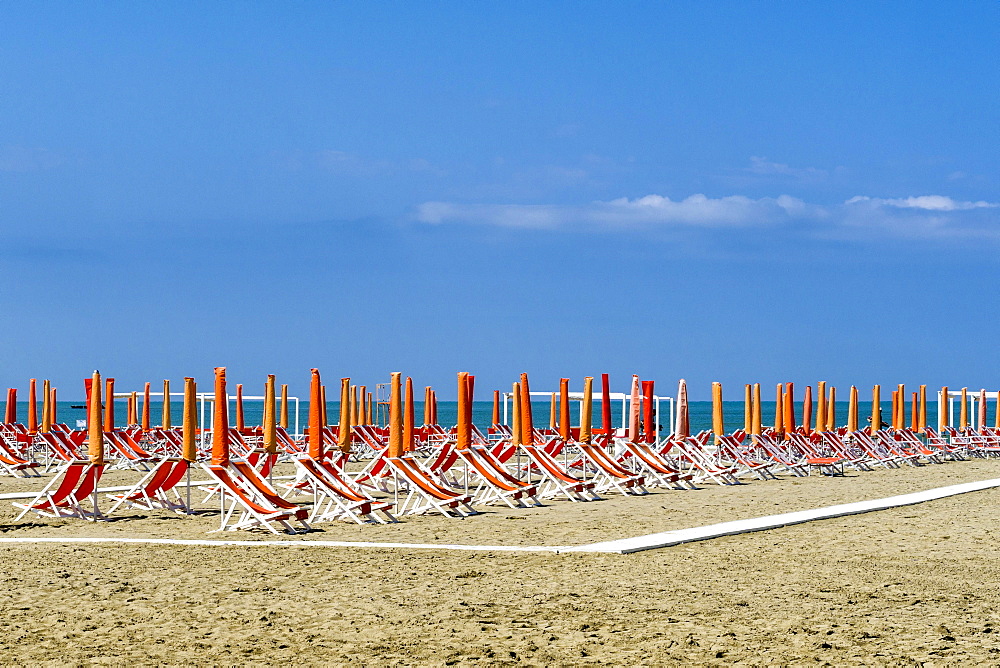 Empty orange deckchairs and sunshades on beach, early season, Viareggio, Tuscany, Italy, Europe