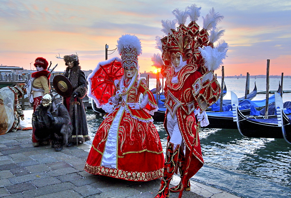 Disguised couple with Venetian masks at the lagoon, behind island San Giorgio, carnival in Venice, Italy, Europe