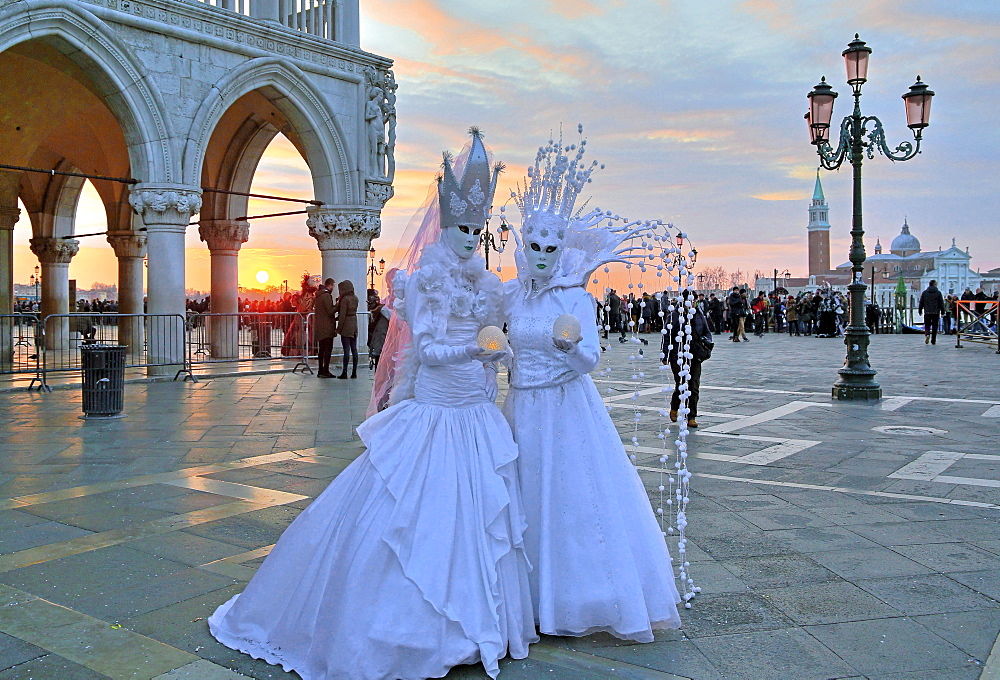 Disguised couple with Venetian masks at sunset, behind island of San Giorgio, carnival in Venice, Italy, Europe