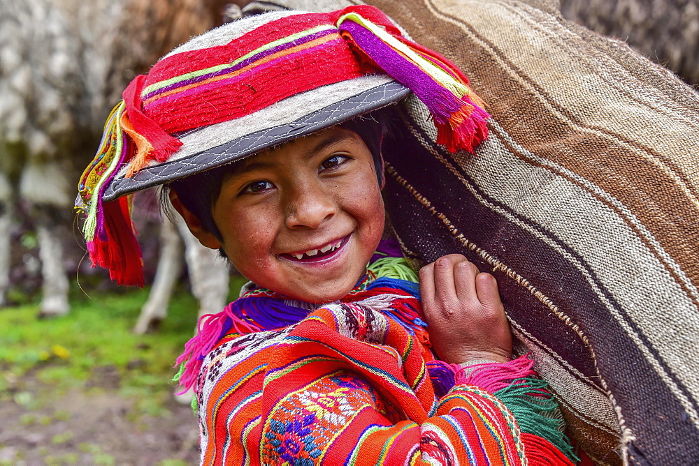 Indio Boy in traditional costume with poncho and hat, carrying bag, near Cusco, Andes, Peru, South America