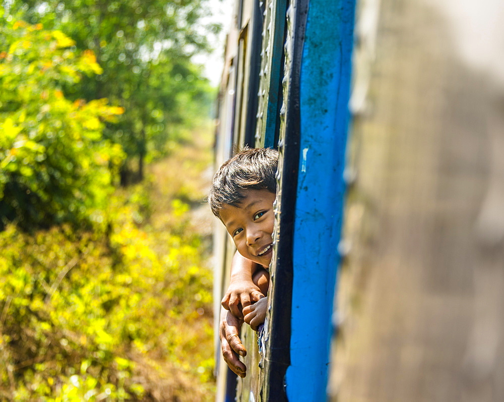 Small local boy looking out of moving train, Yangon Circular Railway, Yangon, Myanmar, Asia