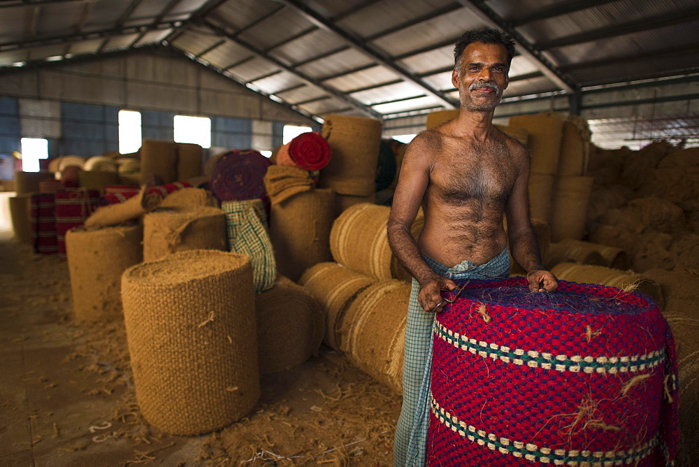 Worker with rolled coconut fibre mats or coir mats, coconut fibre industry, factory, Alappuzha, Kerala, India, Asia