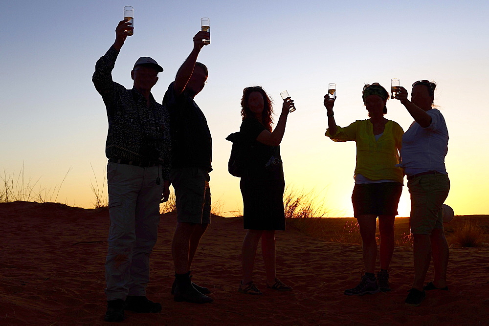 Tourists at the sundowner with glass in hand, backlight at sunset, Kglagadi Transfrontier Park, Northern Cape, South Africa, Africa