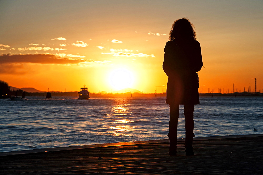 Woman watching the sunset on the Zattere promenade, Venice, Italy, Europe