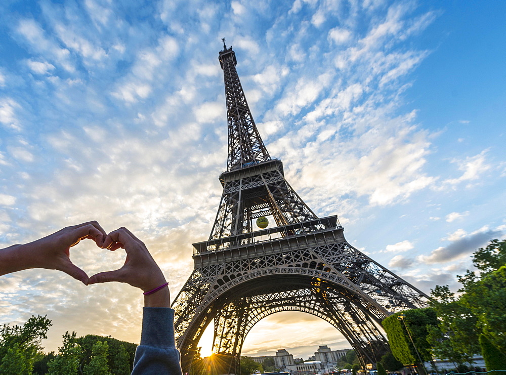 Hands forming heart, sunset behind Eiffel Tower, Paris, Ile-de-France, France, Europe