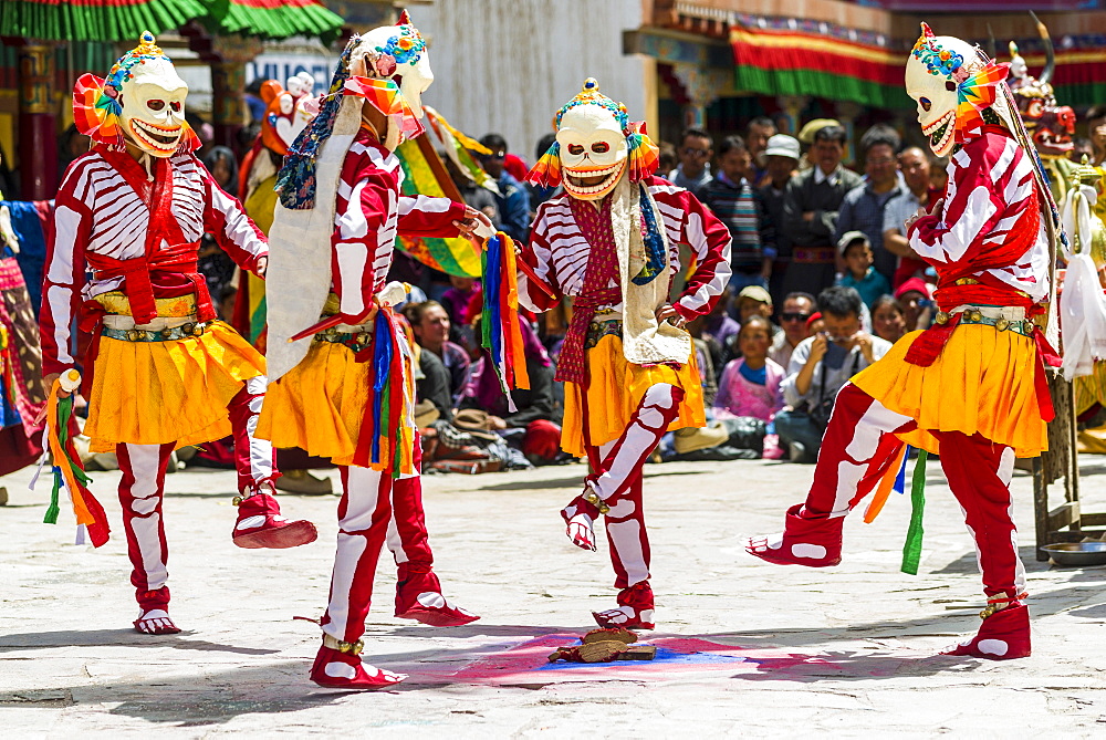 Monks with big wooden masks and colorful costumes are performing ritual dances at Hemis Festival in the courtyard of the monastery, Hemis, Jammu and Kashmir, India, Asia