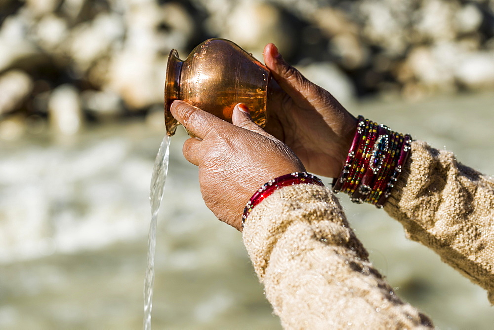 A female pilgrim praying, offering the holy water, at the banks of the river Ganges, Gangotri, Uttarakhand, India, Asia