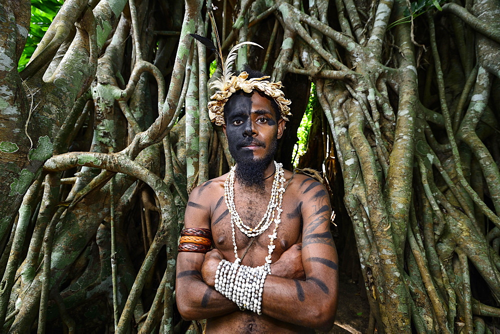 Tribal warrior in front of the roots of the banyan tree (Ficus benghalensis), Ekasup Cultural Village, Efate Island, Vanuatu, South Sea, Oceania