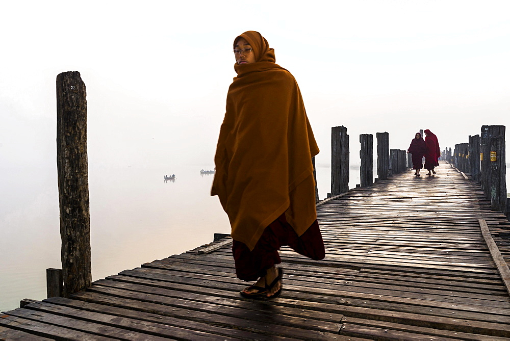 Monks walking on a teak bridge, U Bein Bridge, across Thaungthaman lake, in the morning, Amarapura, Mandalay Division, Myanmar, Asia