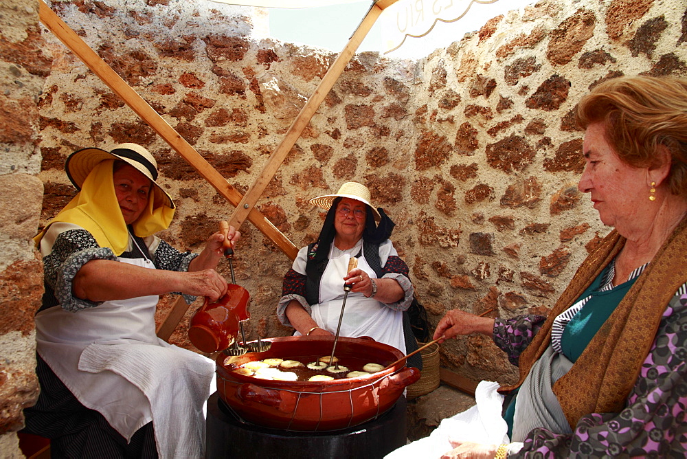 Elderly women in traditional costume baking ""bunyols"", typical fried dough balls, at a traditional handicraft fair, Ibiza, Spain, Europe