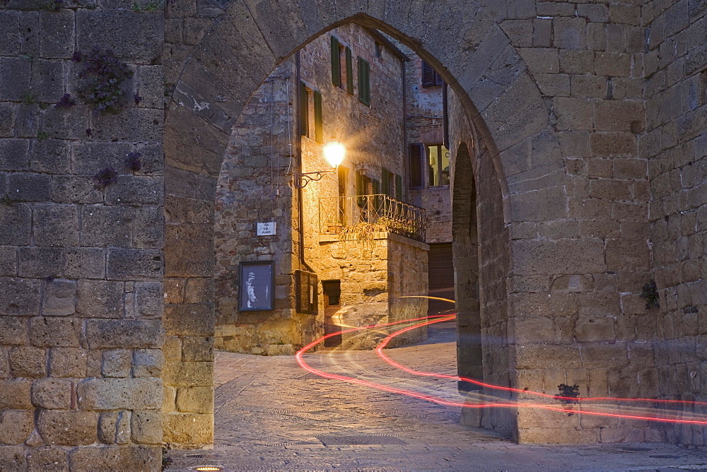 City gate with the light trace of a passing car, Monticchiello, Val d'Orcia region, Province of Siena, Tuscany, Italy, Europe