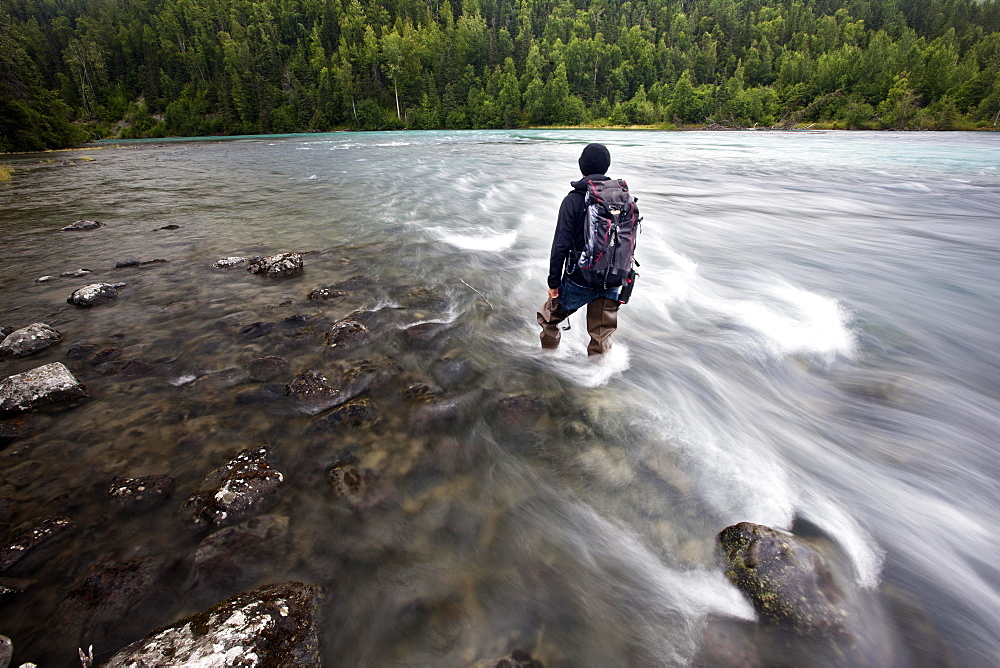 Man wearing fishing boots on the bank of Lowe River near Valdez, Alaska, USA, North America