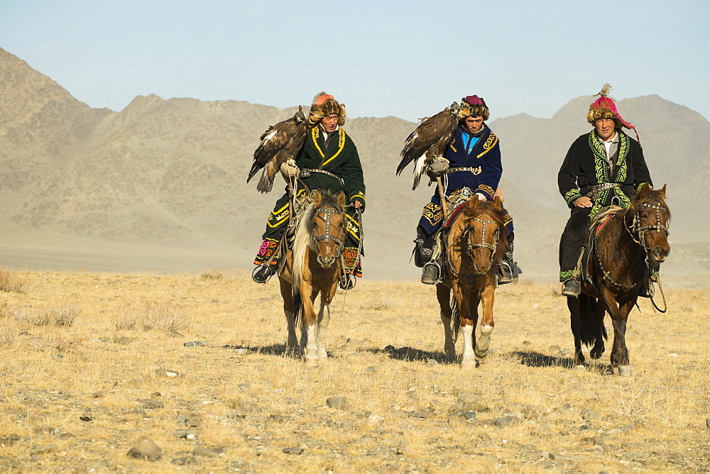 Three Kazakh eagle hunters on their horses on the way to the Eagle Festival in Sagsai, Bayan-Oelgii Aimag, Mongolia, Asia