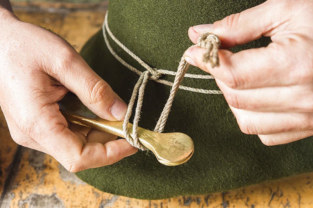 Tightening the shaping cord around a wool felt hat, using iron tool, hatmaker workshop, Bad Aussee, Styria, Austria, Europe