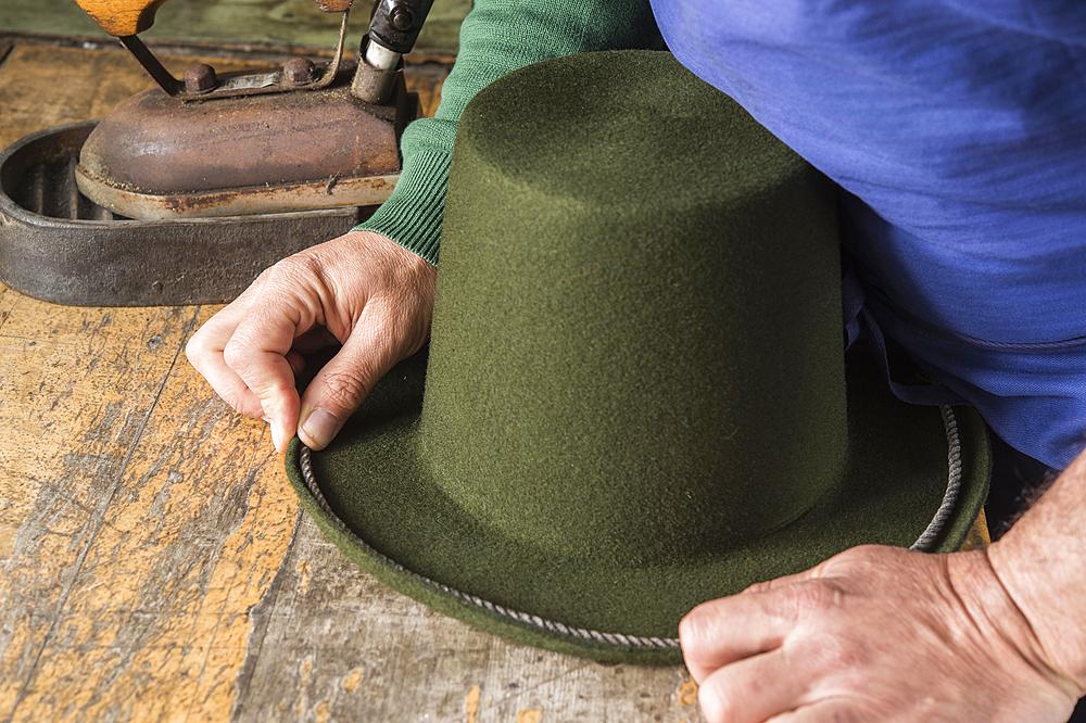 Hands holding cord on dry wool felt hat with shaped edge, hatmaker workshop, Bad Aussee, Styria, Austria, Europe