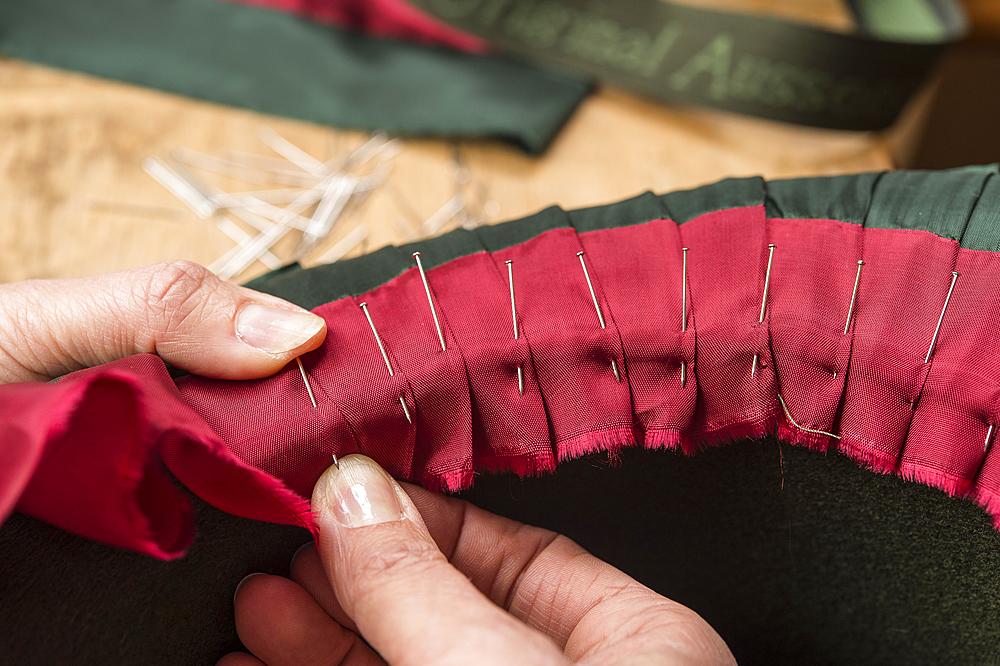 Hands folding and fastening silk ribbon using pins, inner lining of a wool felt hat, hatmaker workshop, Bad Aussee, Styria, Austria, Europe